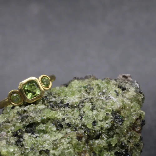 Anillo trilogía de oro amarillo 9k con peridoto central talla cushion y dos peridotos redondos en engaste bisel