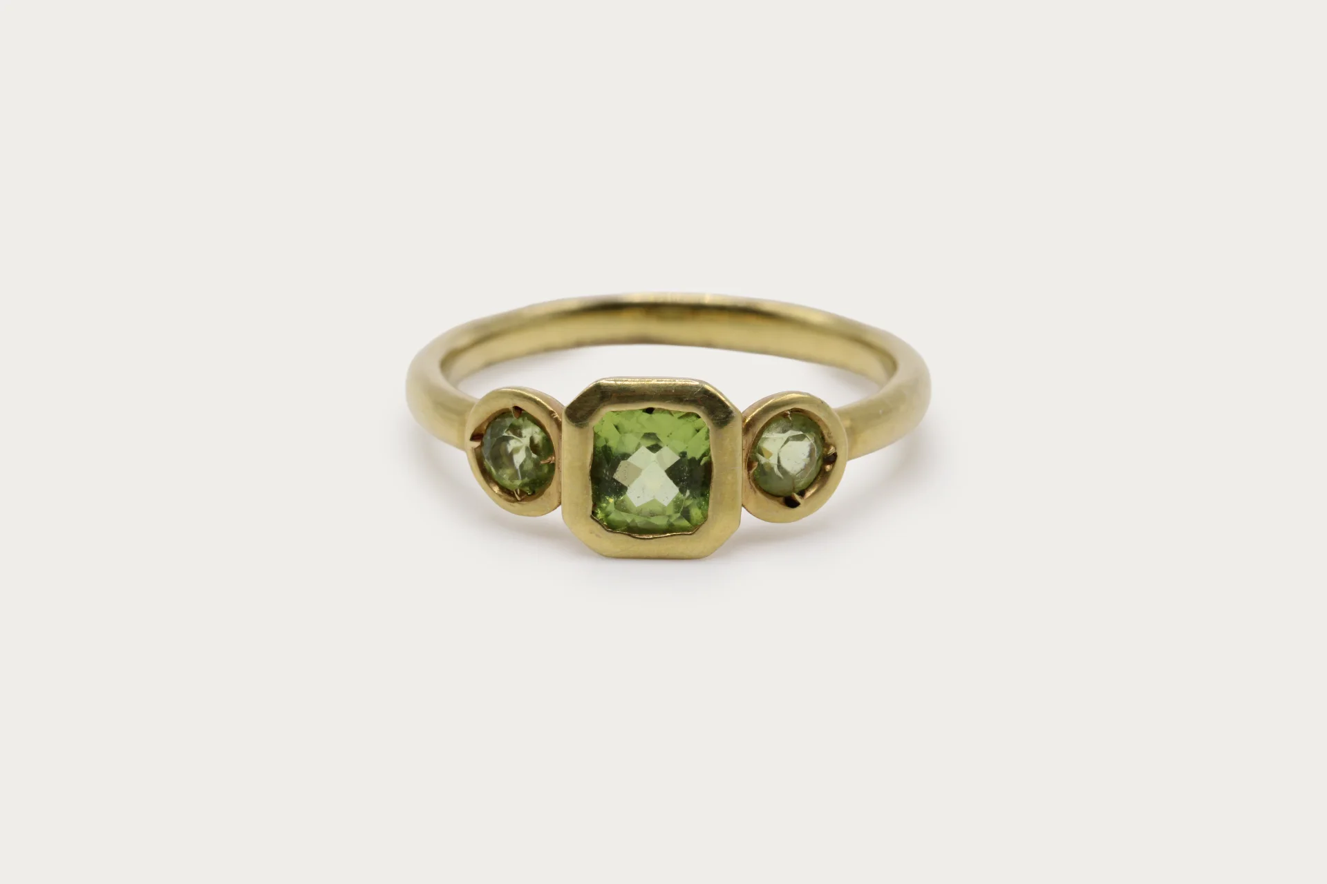 anillo-oro-amarillo-9k-peridoto-trilogia-cushion (4) Anillo trilogía de oro amarillo 9k con peridoto central talla cushion y dos peridotos redondos en engaste bisel