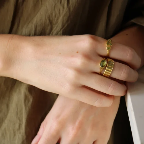 Anillo trilogía de oro amarillo 9k con peridoto central talla cushion y dos peridotos redondos en engaste bisel