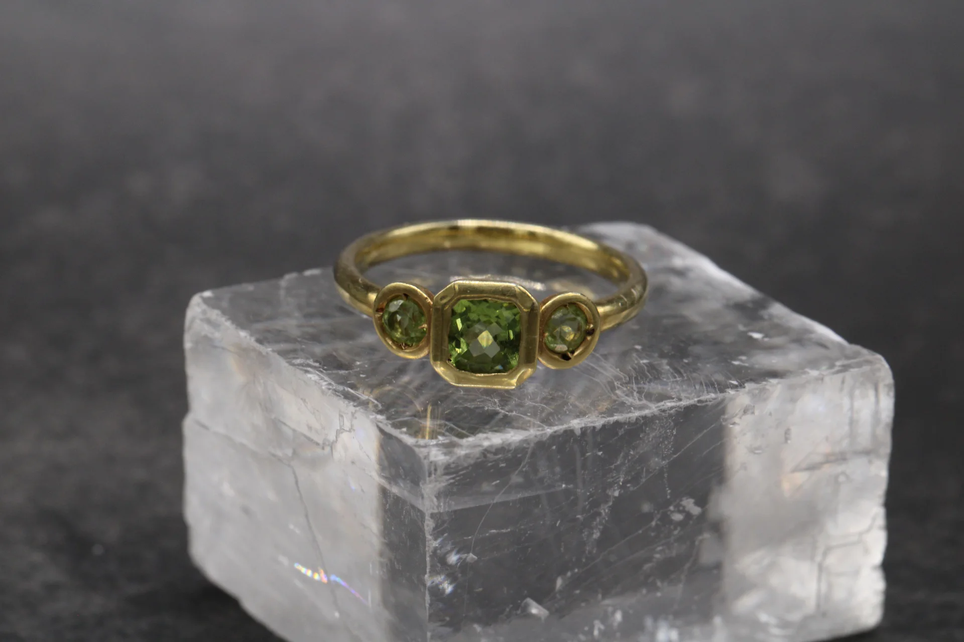 anillo-oro-amarillo-9k-peridoto-trilogia-cushion Anillo trilogía de oro amarillo 9k con peridoto central talla cushion y dos peridotos redondos en engaste bisel