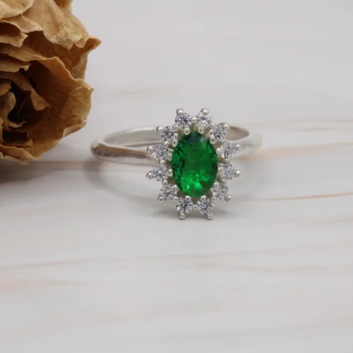 Anillo rosetón de oro blanco 18k con esmeralda central de 7x5mm y halo de 12 diamantes H/VS