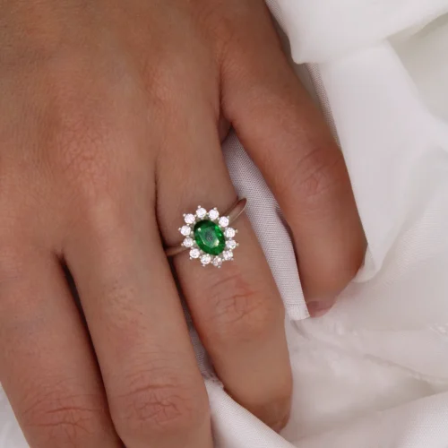 Anillo rosetón de oro blanco 18k con esmeralda central de 7x5mm y halo de 12 diamantes H/VS