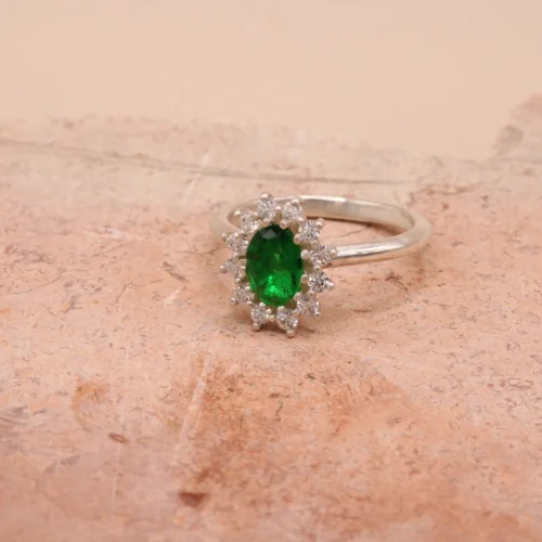 Anillo rosetón de oro blanco 18k con esmeralda central de 7x5mm y halo de 12 diamantes H/VS
