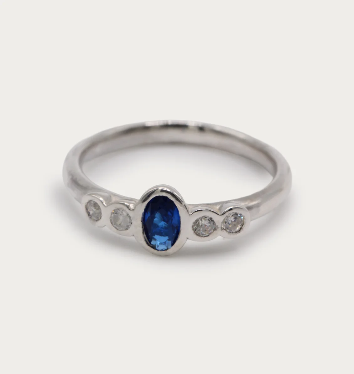 anillo-oro-blanco-18k-zafiro-diamantes-brillante Anillo de oro blanco 18k con zafiro central azul y cuatro diamantes talla brillante G/VS, engaste en bisel