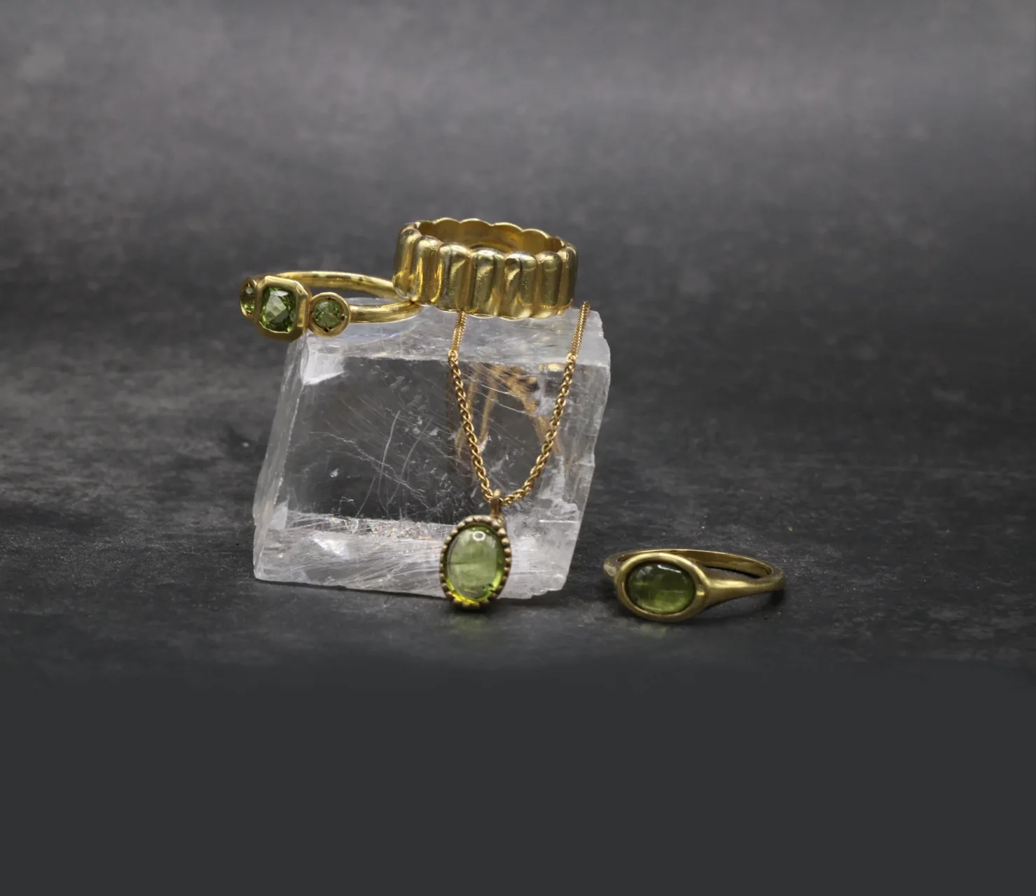 Tres anillos de oro amarillo 9k sobre roca: anillo trilogía de peridotos, anillo signet con peridoto cabujón y anillo banda texturizada