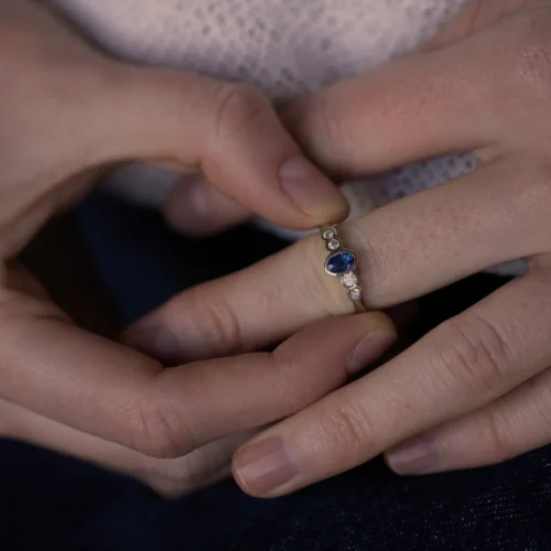 Anillo de oro blanco 18k con zafiro central azul y cuatro diamantes talla brillante G/VS, engaste en bisel